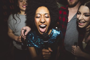 Exuberant young female millennial singing karaoke