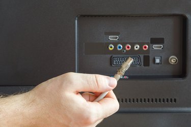 Man's hand holding coaxial cable. Back of tv. Television signal. Problem and solution.