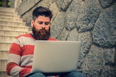 Young hipster sitting and using laptop