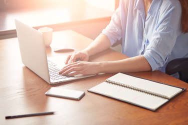 Cropped view of a young businesswoman typing on her laptop