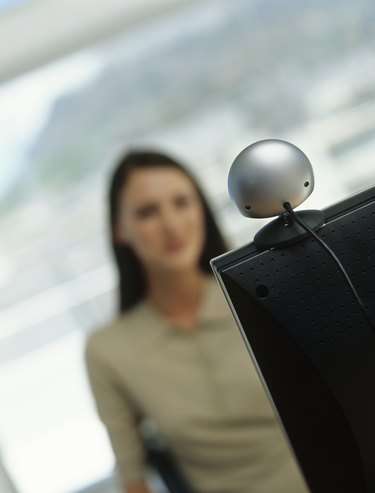 Woman using computer with web cam,focus on computer