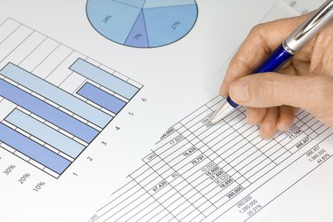 Hand with Pen Figures and Graphs in Blue