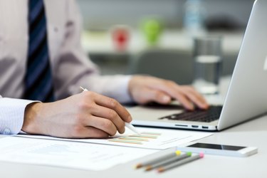 Business Person reading Data on paper Charts and Computer