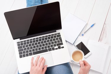woman working at home at laptop with cup of coffee