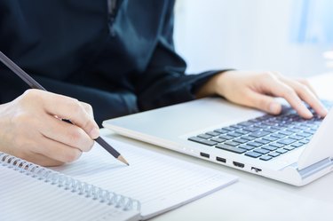 selective focus, Cropped shot of  hands writing while using laptop.